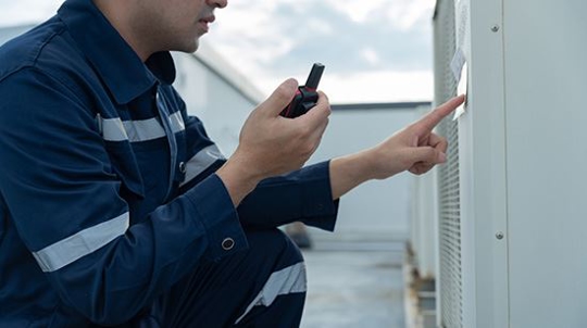 Home service worker pointing out feature on AC unit