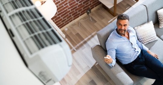 man adjusting heat pump in home