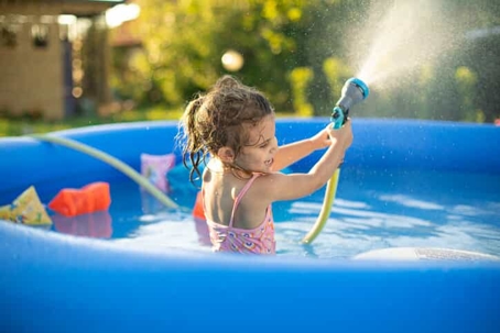 a girl spraying a hose in a pool